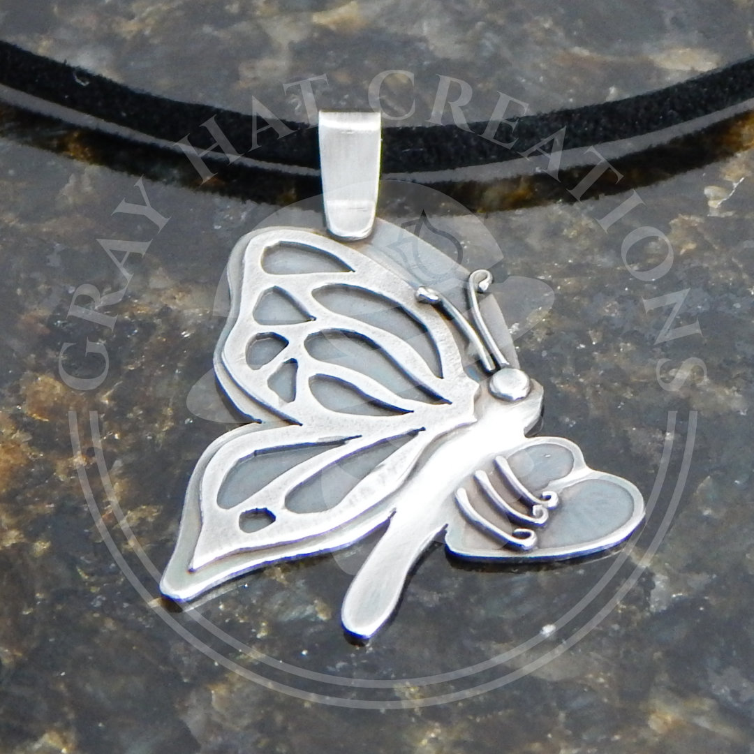 Sterling pendant of a butterfly holding a broken heart